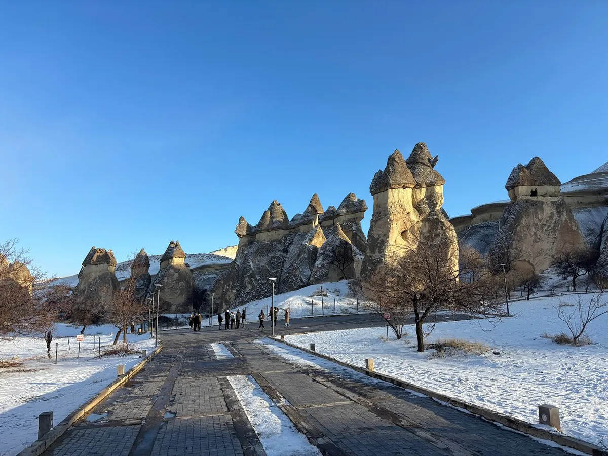 A road through a snowy Cappadocia landscape with rock formations